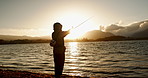 Person, fishing and water in morning, sunrise and sport by ocean, lake and river with equipment in nature. Fisherman, line and catch fish for games, food and silhouette in sunshine, dawn and horizon