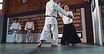 Aikido, sensei and Japanese students with discipline, fitness and action in class for defence or technique. Martial arts, people or fighting with training, uniform or confidence for culture and skill