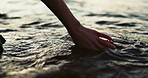 Closeup, hand and water in morning by sea with touch, waves and nature on vacation in sunshine. Person, fingers and outdoor vacation by river, lake and ocean in environment with ripple in Japan
