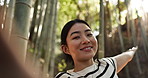 Face, woman and video call in forest, nature and show scenery of bamboo trees for live streaming travel blog. Portrait of happy Japanese tourist, influencer or broadcast vlog in woods on social media