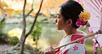 Japanese, fashion and woman in kimono outdoor walking with umbrella in garden or forest. Traditional, style and girl with dress robe from culture relax in nature, woods or park with peace and zen