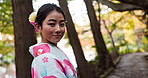 Japanese, kimono and woman with fashion outdoor in garden or forest with a smile. Traditional, style and happy portrait of girl in culture dress robe and relax in nature, woods or park with pride