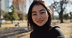 Japanese woman, face and happy for relax in city, natural glow and lens flare in urban outdoor. Young person, smile or portrait in tokyo in park for wellness, leisure or positive on vacation in town