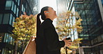 Japanese woman, phone and earphones in city with smile, walking and listening to music by buildings. Person, pedestrian and smartphone with audio streaming subscription with radio app on metro street