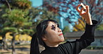 Outdoor, Asian woman and sunshine with a smile, nature and leaf with joy, weekend break and peaceful. Japanese person, outside and girl with sky, summer and happy with fresh air, travel and holiday