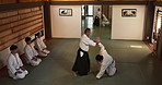 Group of men in dojo with sensei for aikido training, fitness and challenge with action, exercise and coaching. Teaching, learning and students in traditional Japanese martial arts class with mentor.