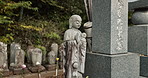 Garden sculpture in traditional Japanese graveyard with peace, calm and quiet landscape with memorial tombstone. Stone Buddha statue in outdoor cemetery with zen, Asian culture and spiritual history.