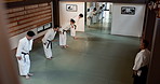 Japanese students, bow or learning martial arts in dojo for practice, body movement or self defense. Combat demonstration, people or black belt training workout for fighting education or Aikido class