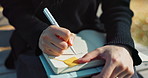 Closeup, writing and notes in park with hands, person and journalist with ideas, planning or development of story. Writer, poet or creative worker with pen, book and paper for notes for job in Japan