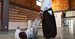 Woman in dojo with sensei for aikido fight training, fitness and challenge with action, exercise and coaching. Teaching, learning and student in traditional Japanese martial arts class with aikidoka.