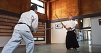 Aikido with sensei, wooden sword and student training for fitness, fight and action in dojo. Teaching, learning and men in traditional Japanese martial arts class with aikidoka, bokken and challenge.