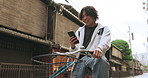 Bicycle, phone and man riding by building for exercise or transportation to college academy. Cellphone, travel and young male student driving a bike to university for carbon footprint by houses.