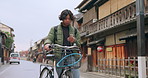 Bicycle, cellphone and man riding by building for exercise or transportation to college academy. Fitness, phone and young male student driving a bike to university for carbon footprint by houses.