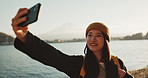 Selfie, travel and Japanese woman by lake for holiday, vacation and adventure in Japan. Happy, smile and person take picture on smartphone by water for social media post, memories and online blog