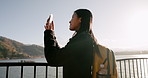 Japanese woman, lake and phone for photography, memory and post on web blog for travel with backpack. Girl, person and outdoor with smartphone by water, river and photoshoot for social media in Tokyo