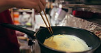 Cooking, chopsticks and person with pan on gas stove at market for meal preparation, eating and nutrition. Culinary, flame and closeup of chef hands with utensils for egg cuisine, dinner and supper