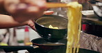 Cooking, food market and person with noodles on gas stove for meal preparation, eating and restaurant. Japanese culinary, flame and closeup of chopsticks to prepare lunch, cuisine dinner and supper