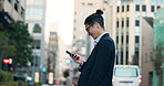 Cellphone, networking and Japanese businessman in city reading company email on technology. Career, travel and professional young male person scroll or browse on a phone with earbuds in urban town.