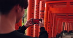 Phone, man and picture of torii gates on vacation, holiday trip or travel for tourism. Smartphone, hands and closeup photography of Fushimi inari-taisha in Kyoto Japan on mobile technology outdoor