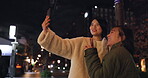 Japanese, women and selfie outdoor at night with hand gesture, peace sign and happy in city street. Friends, people and phone with smile for travel, adventure and social media update in urban town