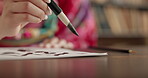 Closeup of hand, brush and Asian writing or script with paper, document and creativity, calligraphy and traditional text. Japanese font, writer with black ink and person at desk with art and tools