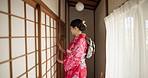 Culture, walking and a Japanese woman in a house for comfort, relax and opening a door in the morning. Architecture, hallway and a young girl in a traditional room or home for local accommodation