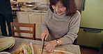 Senior woman, knife and vegetables in kitchen with cutting, smile and meal prep for wellness in retirement. Elderly Japanese person, ready and happy with food, blade and wooden block for nutrition
