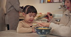 Mom, chopsticks and noodles in home with child, feeding and teaching for nutrition, diet and health. Japanese family house, mother and daughter with food, helping hand and development for wellness