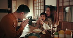 Japanese parents, girl child and dinner with bow, smile and teaching gratitude with noodles, night and nutrition in home. Kid, mother and dad for food, diet and dining room at family house in Tokyo