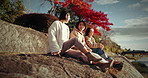 Friends, sitting conversation and outdoor with travel, gen z and happy discussion together in Japan. Student group, Japanese woman and talking by a bridge on vacation and holiday with communication