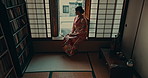 Thinking, culture and traditional Asian woman by window for reflection, calm and wellness in morning. Kimono, happy and person in home with view for thoughtful, wondering and relax in living room
