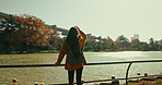 Woman, lake and backpack for view, back or thinking for vision, memory or reflection on travel journey. Girl, person or tourist with bag in nature, sunshine or autumn in environment by water in Tokyo