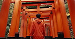 Inari shrine, man and shinto temple with back for religion, ideas and walking in nature for connection to god. Japanese person, outdoor and trees with pillar, spiritual journey and vision in Kyoto