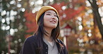 Japanese, park and woman travel in autumn with trees, leaves and nature in Kyoto. Happy, girl and outdoor on vacation, holiday or experience on journey in environment with a smile for winter or fall