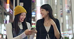 Japanese people, phone and city for night travel, walking and talk of social media, news or information. Women or young friends reading blog on mobile with network, internet or communication in Tokyo