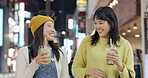 Japanese, drink and friends walking in the city at night with happy conversation of travel. Tea, takeaway or women smile together talking on coffee break with bonding, experience and communication