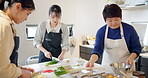 Cooking class, women and chopping to cook, chef and japanese food in kitchen, professional and skill. Restaurant, teaching and course for culinary skills, working together and aprons for cleanliness