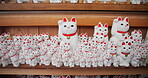 Cats, Gotokuji and temple of manekineko in Japan for luck, success and gratitude outdoor on wooden furniture. Sculpture, figure and traditional doll in Tokyo for happiness, lucky fortune and culture