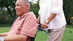 Man, wheelchair and person assistance in park or relax weekend for holiday, nature or environment. Male senior with a disability, marriage and together or retirement explore or happy, rest or outdoor