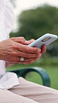 Person, hands and typing on cellphone in park for online communication or reading, research or conversation. Fingers, texting and garden bench with digital device for email, technology or network