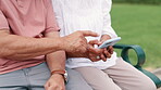 Senior couple, hands and cellphone on bench in park, typing and internet connection with bonding together. Mature people, mobile phone or struggle with technology, learning or help on weekend in city