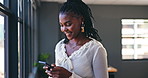 Phone, networking and professional black woman in the office browsing on social media or the internet. Smile, technology and African female person scroll on mobile app with cellphone in workplace.