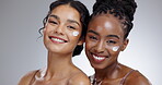 Women, cream and skincare with diversity in studio with facial treatment, happiness or glowing skin. Friends, model and portrait with smile for cosmetics, dermatology or body care on gray background
