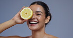 Face, lemon and woman with natural beauty, vegan or eco friendly product with wellness for skin in studio. Happiness, excited and fruit, vitamin c and citrus with cosmetic care on grey background
