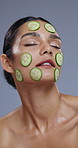 Wellness, cucumber and face of woman on blue background for skincare, beauty and cosmetics. Dermatology, spa and vertical of person with vegetable for nutrition, organic or natural benefits in studio