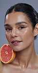 Face, grapefruit and woman with natural beauty, vegan or eco friendly product, wellness for skin in studio. Portrait, dermatology and fruit, vitamin c and citrus with cosmetic care on grey background
