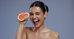 Skincare, squeeze grapefruit and face of woman on blue background for wellness, beauty and cosmetics. Dermatology, portrait and person with fruit for nutrition, organic and natural benefits in studio