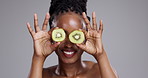 Skincare, kiwi and face of black woman on gray background for beauty, facial and cosmetics. Dermatology, spa and person with fruit on eyes for nutrition, organic and natural benefits in studio