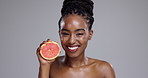 Grapefruit, happy beauty and face of woman in studio for vitamin c benefits, detox or glow on grey background. Portrait, african model or citrus fruits for sustainable skincare, eco cosmetics or diet