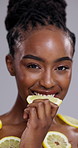 Black woman, nutrition and eating lemon for vitamin C, beauty or detox on a gray studio background. Portrait of African female person, face or model biting natural organic citrus fruit for wellness